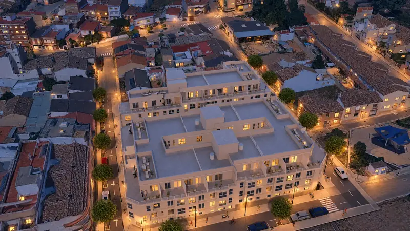 Fachada del edificio al anochecer, con las ventanas y los balcones encendidos