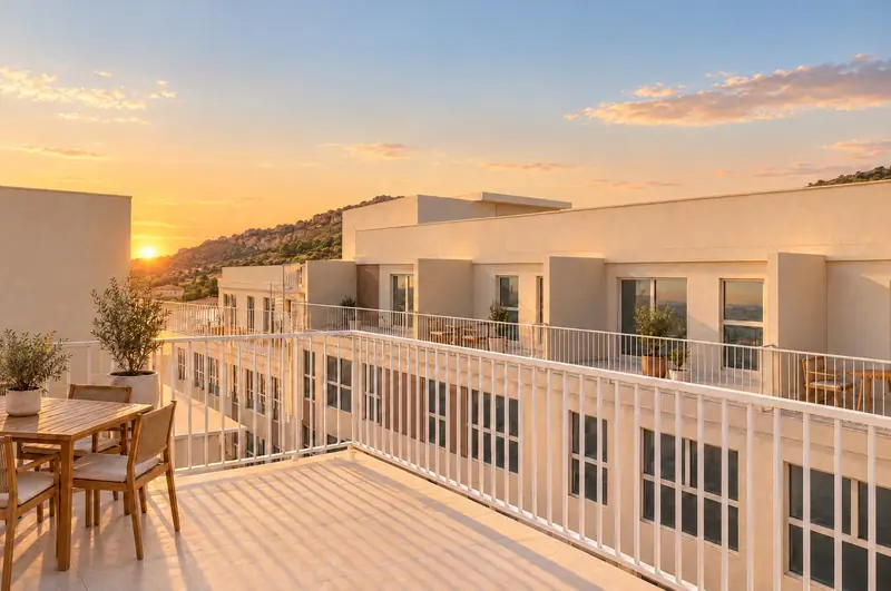 Terraza de ático con mesa y sillas al atardecer, con el otro bloque y la sierra al fondo